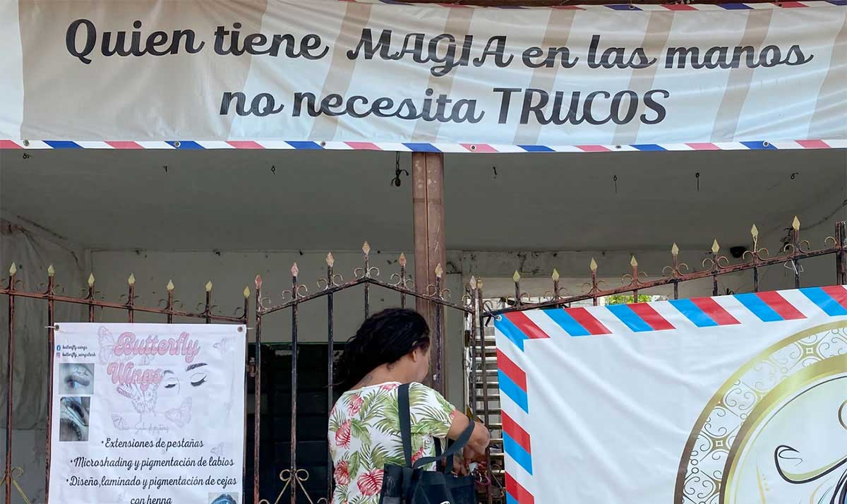 Mujer abriendo la reja de una estética